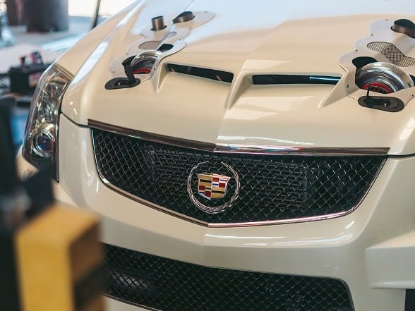 Close-up of a white Cadillac with racing modifications and custom headlight components.