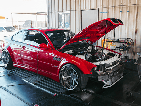 Red custom car with open hood at Black Market Racing workshop.