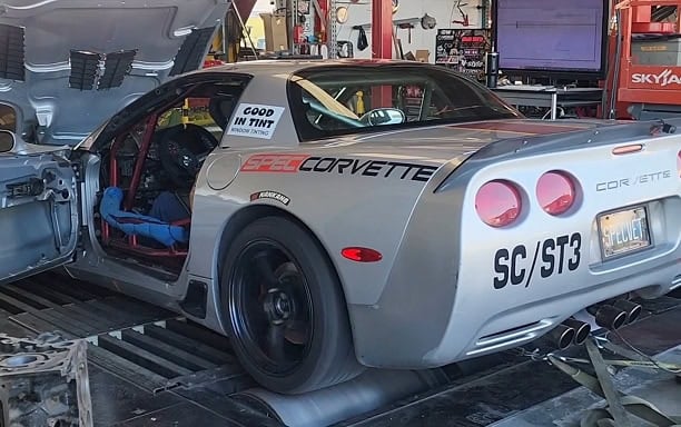 Corvette race car with SC/ST3 branding in a garage setting.
