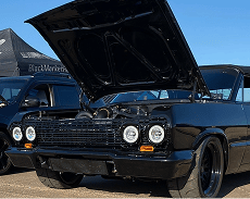 Black classic muscle car with open hood at Black Market Racing event.
