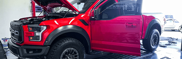 Red custom Ford truck with open hood and black wheels at Black Market Racing.