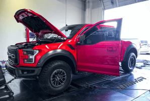 Red custom off-road truck with open hood and door at Black Market Racing.