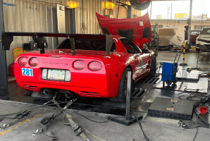 Red sports car on dynamometer for performance testing at Black Market Racing.