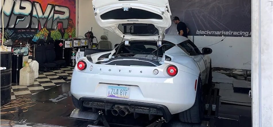 Silver Lotus Evora at Black Market Racing workshop with open engine hood.