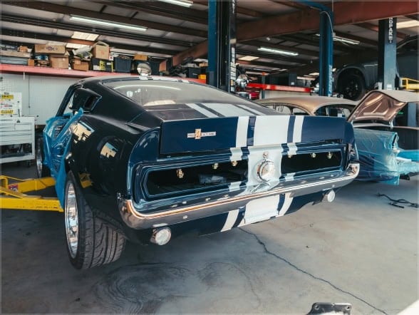 Vintage muscle car with racing stripes in a garage setting.