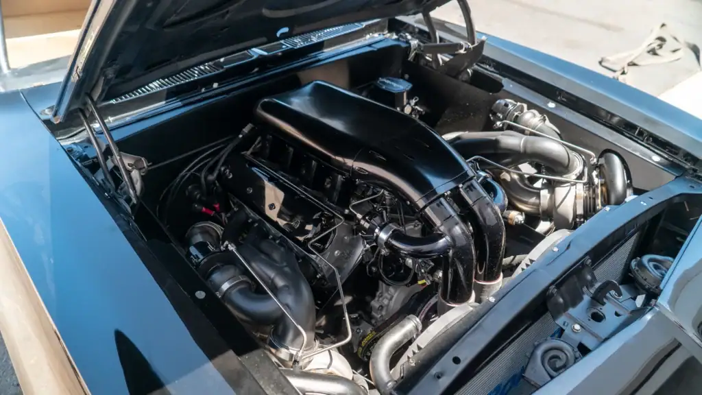 Turbocharged engine and custom charge piping in the engine bay of a blue build at Black Market Racing