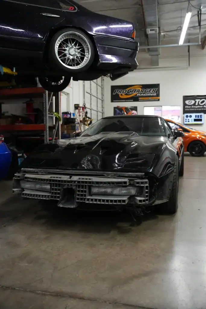 Black Market Racing workshop with damaged sports car and lifted vehicle.