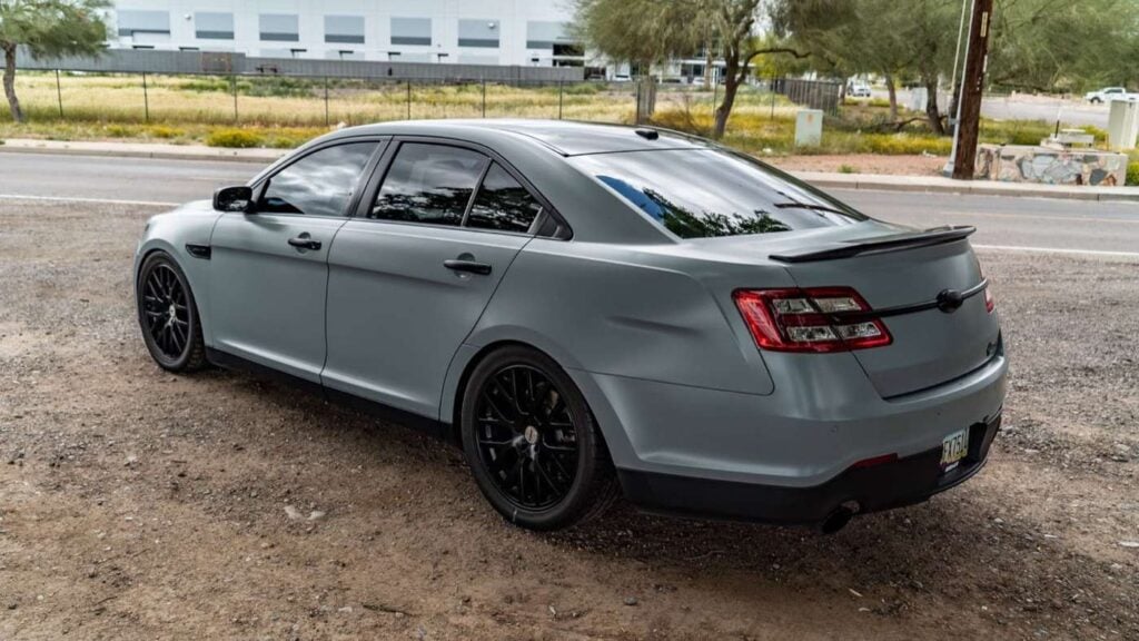 Rear three-quarter view of a matte grey Ford Taurus SHO with a lip spoiler